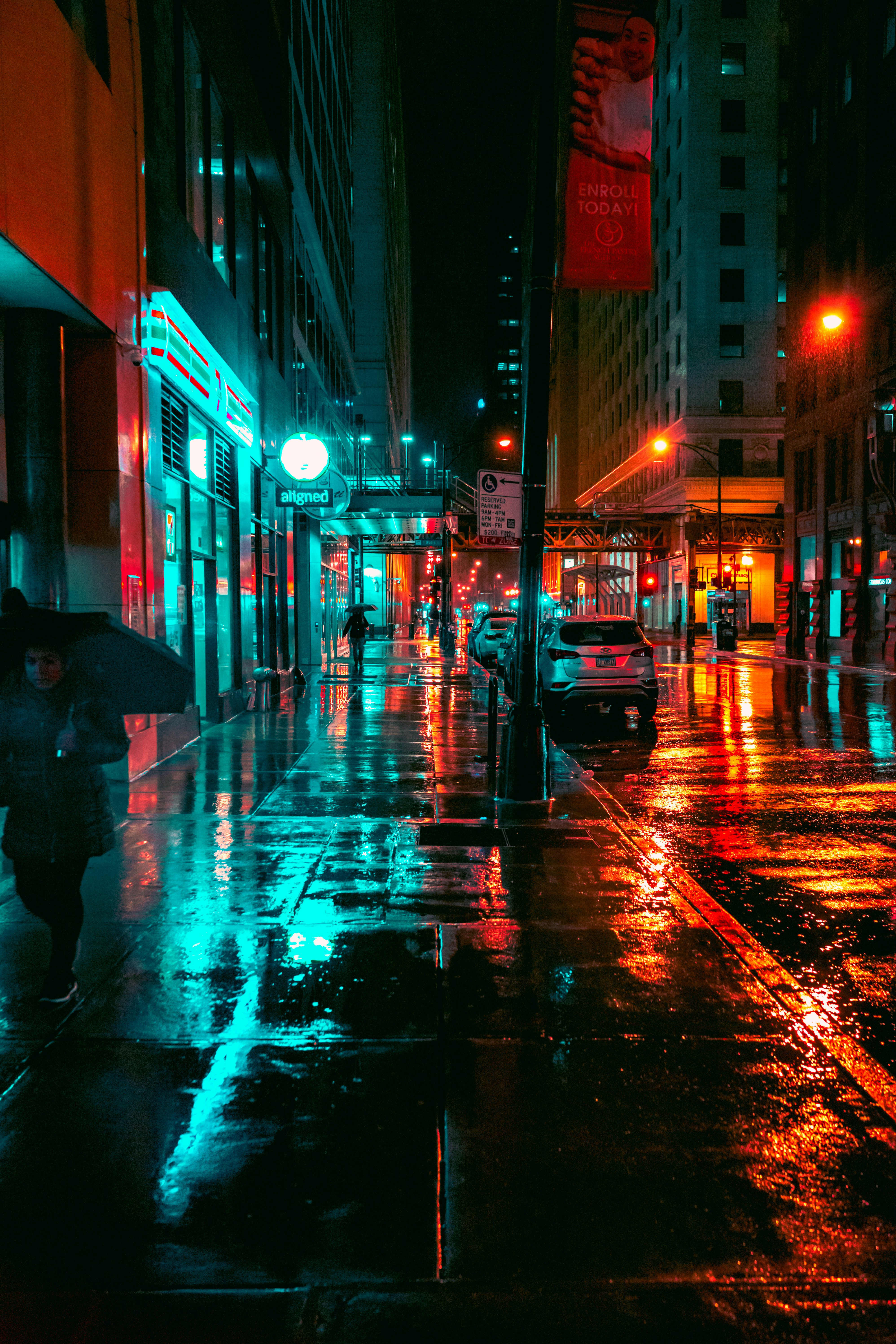 Rainy downtown street at night with cyan neon reflections on wet pavement